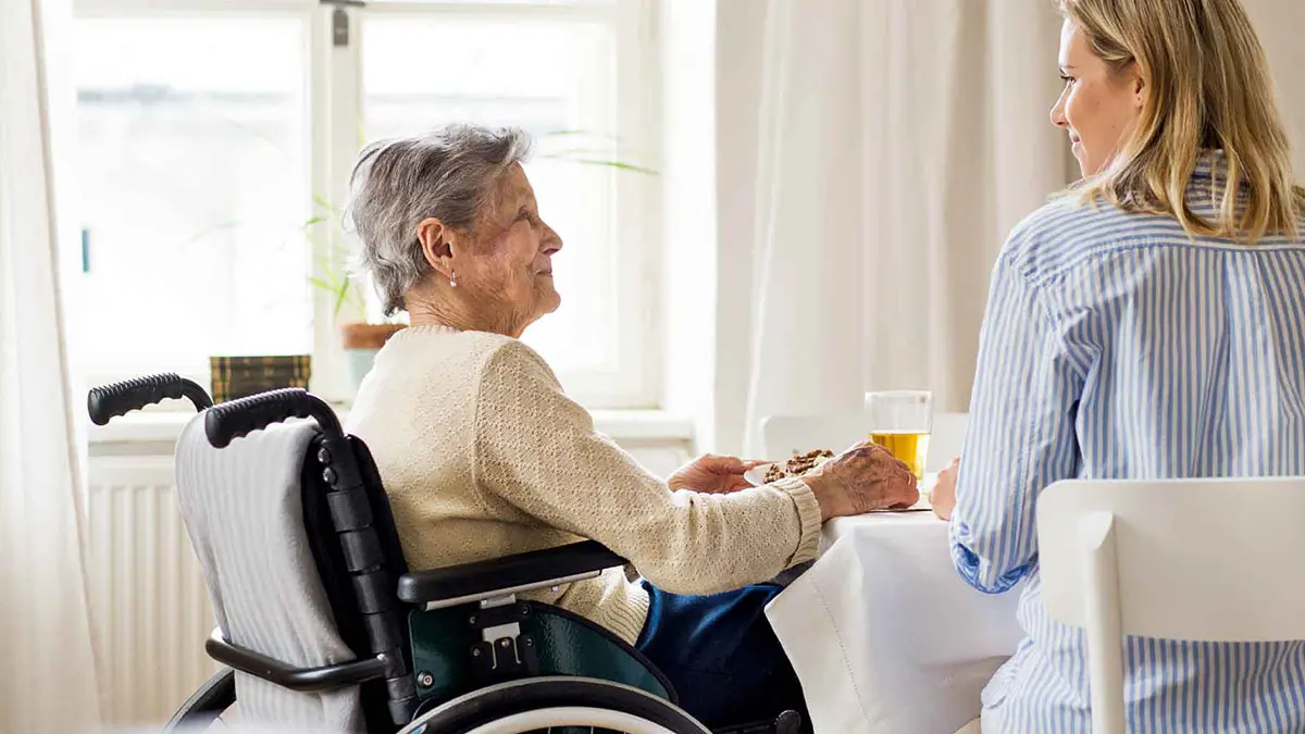 grandmother in wheelchair having breakfast with granddaughter