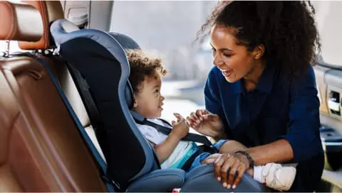 Mom buckling child in car seat