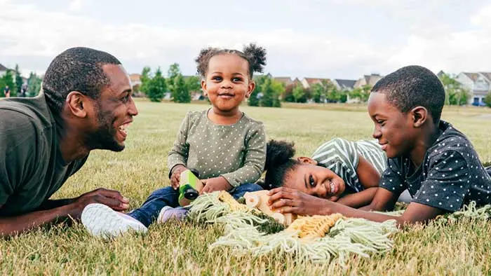 Young father and three kids on a blanket in the park