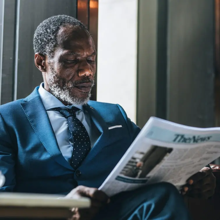 Middle-aged business man wearing a suit and reading a newspaper.