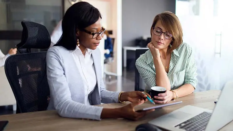 Two women reviewing international payments on a computer