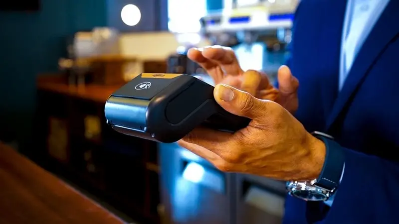 Closeup of a hand holding a credit card reading machine