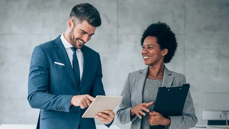 Two colleagues standing together reading a corporate report.