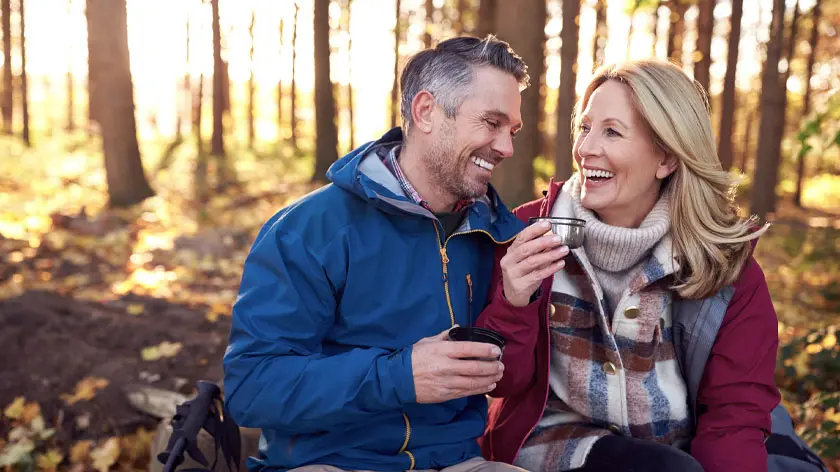 mature couple camping outdoors and drinking coffee