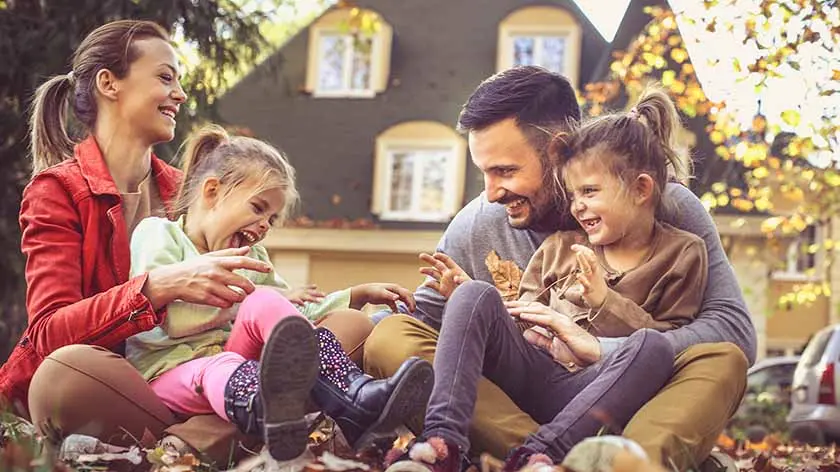 parents playing in leaves with daughters