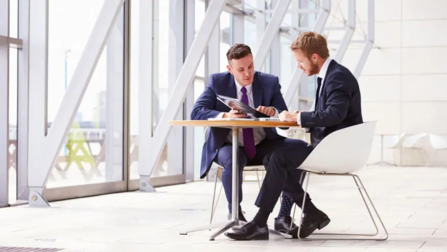 Two men sitting at desk looking over KYC and AML requirements