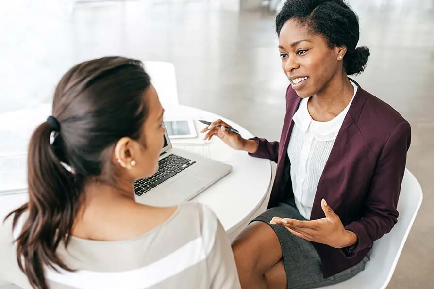 Two women discussing business in front of a laptop