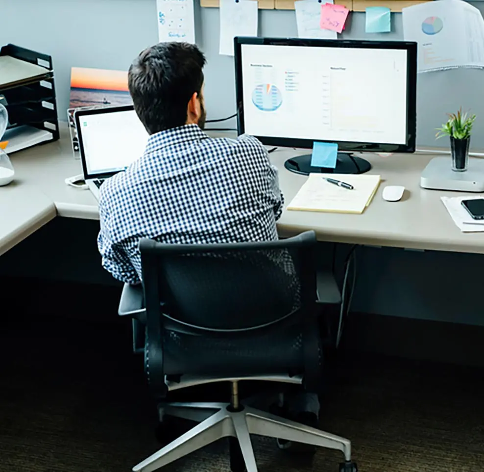 Man sitting at a desk with facing two computer screens
